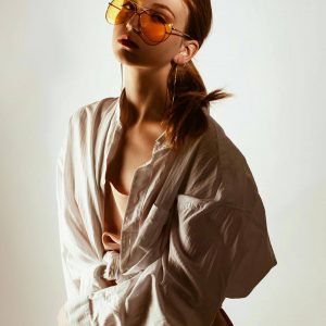 Femme portant une chemise blanche oversize, lumière dorée sur son visage.