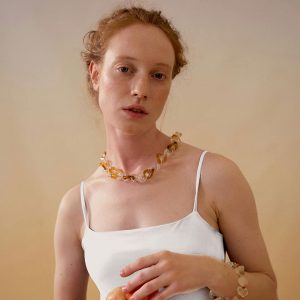 Femme rousse portant un débardeur blanc et un collier naturel