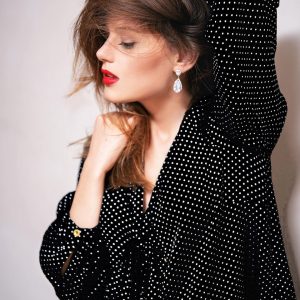 Femme en robe noire à pois, maquillage rouge et pose glamour