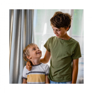 Deux garçons se souriant, le plus grand pose sa main sur l’épaule du plus jeune