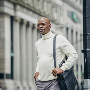 Homme élégant en col roulé blanc consultant son téléphone en ville