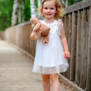 Petite fille en robe blanche tenant un ourson